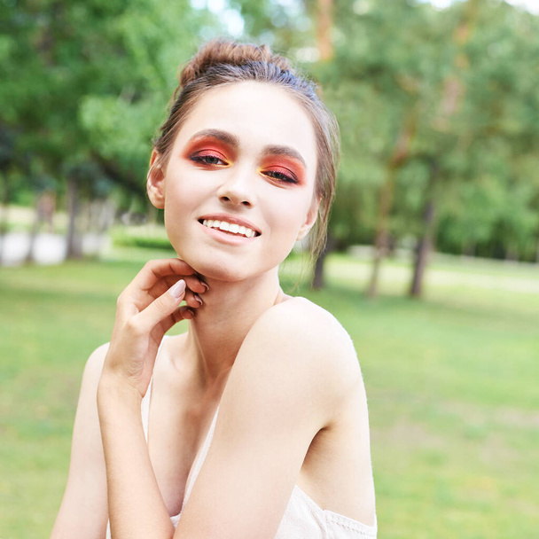 Pretty young woman with bright make up. Outdoor green portrait - Foto, afbeelding