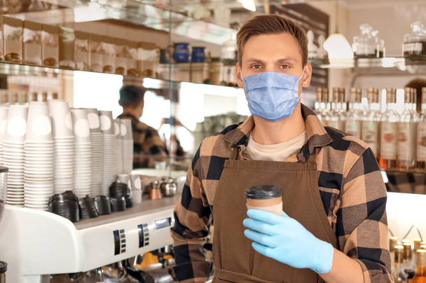 Fiatal férfi barista maszkban a munkahelyén. A járvány fogalma - Fotó, kép