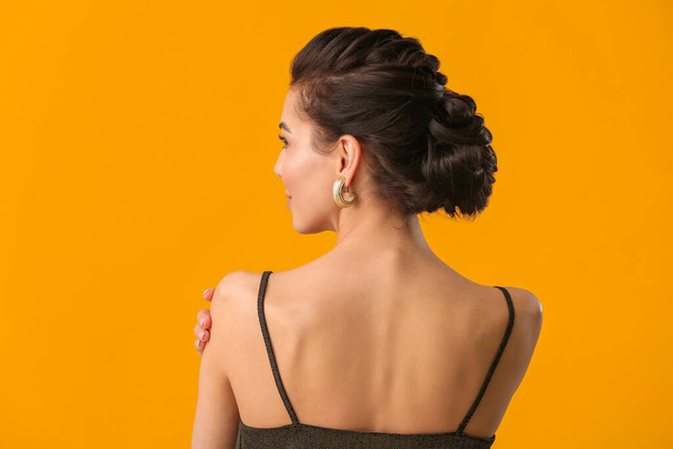 Beautiful young woman with stylish hairdo on color background, back view - 写真・画像