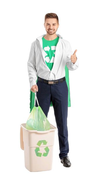 Man dressed as eco superhero with trash bin showing thumb-up gesture on white background - Foto, Imagen