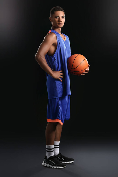Joven jugador de baloncesto afroamericano sobre fondo oscuro
 - Foto, Imagen