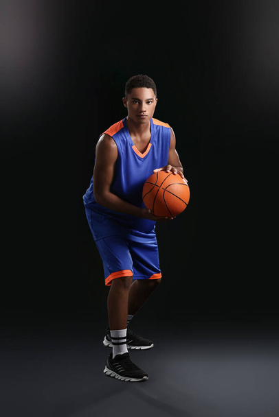 Young African-American basketball player on dark background - Fotoğraf, Görsel