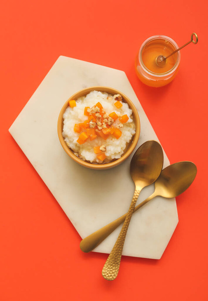 Bowl with boiled rice and pumpkin on color background - Photo, Image