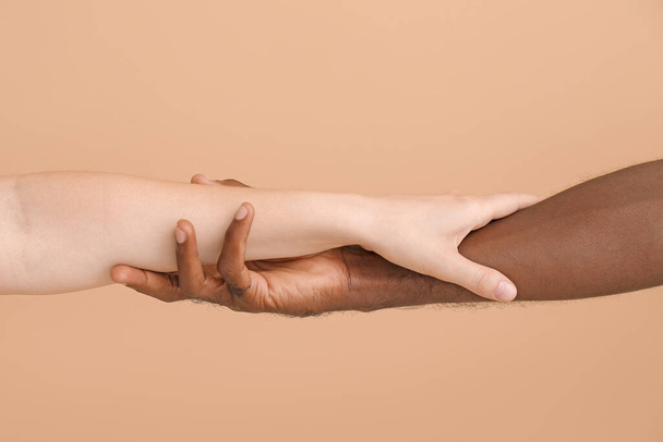 Caucasian woman and African-American man holding hands together on color background. Racism concept - Фото, изображение