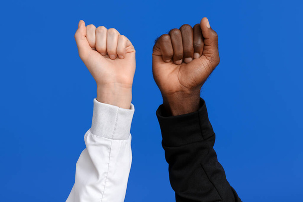 Femme blanche et homme afro-américain avec les poings serrés sur fond de couleur. Concept de racisme - Photo, image