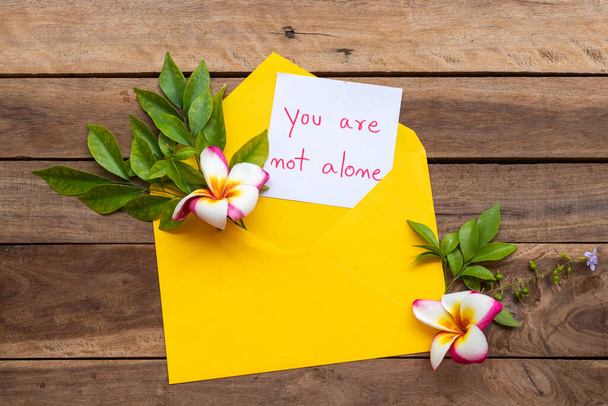 Вы не одиноки в написании открыток почерком желтого цвета с цветами в аранжировке frangipani. - Фото, изображение