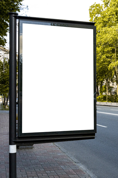 Макет светильника в городе. Небольшой рекламный щит в городе рядом с проезжей части белого пространства для рекламы, вертикальное изображение - Фото, изображение