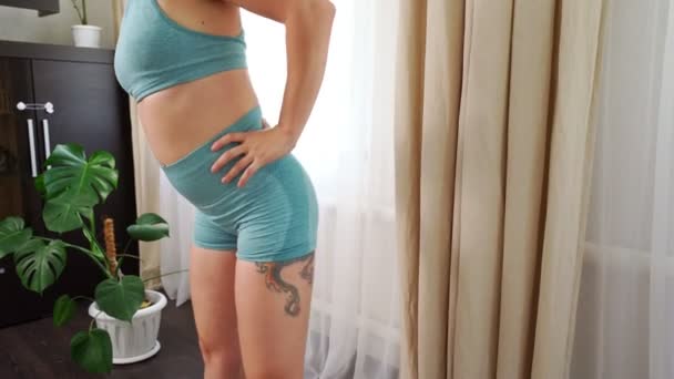 close-up. girl with tattoo in blue tracksuit sports at home, rotation of hips. - Πλάνα, βίντεο