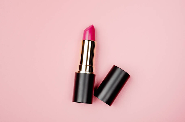 Pink lipstick tube, lip gloss top view. Beauty industry concept. Glamorous makeup accessory close up on pastel pink background. Women fashion product, style. Cosmetology, female elegance attribute. - Photo, Image