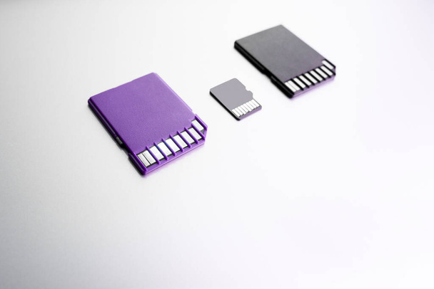 paarse en zwarte SD-geheugenkaarten op wit oppervlak, selectieve focus. zwarte SD geheugenkaart op hout textuur concept - Foto, afbeelding