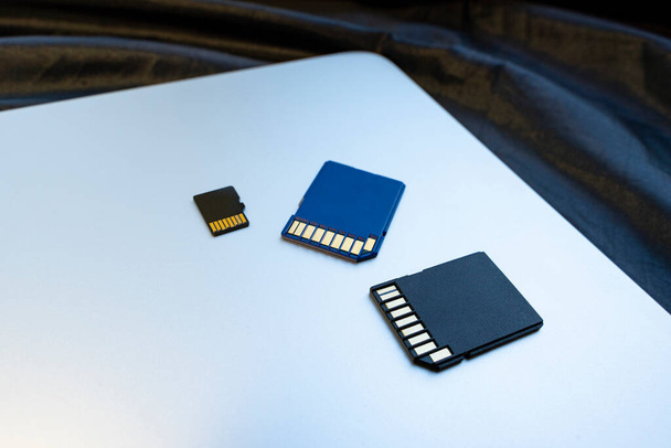 blauwe en zwarte SD geheugenkaarten op zilveren laptop oppervlak, close-up. concept van geheugen, informatieopslag, gegevensopslag - Foto, afbeelding
