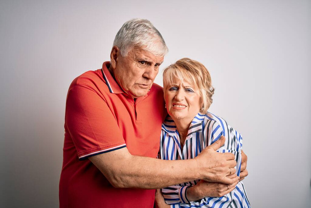 Senior beautiful couple standing together over isolated white background shaking and freezing for winter cold with sad and shock expression on face - Фото, зображення