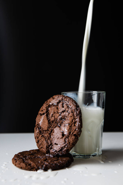 χύνοντας γάλα σε ποτήρι με μπισκότα σοκολάτας. αντίγραφο χώρου - Φωτογραφία, εικόνα