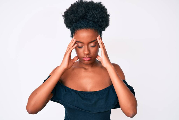 Mujer afroamericana joven que usa ropa casual con la mano en la cabeza para el dolor en la cabeza porque el estrés. padecer migraña.  - Foto, Imagen