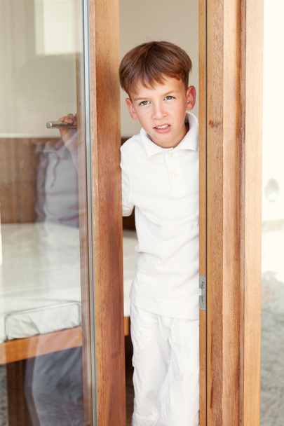 Surprised boy peeks from behind door - Foto, imagen