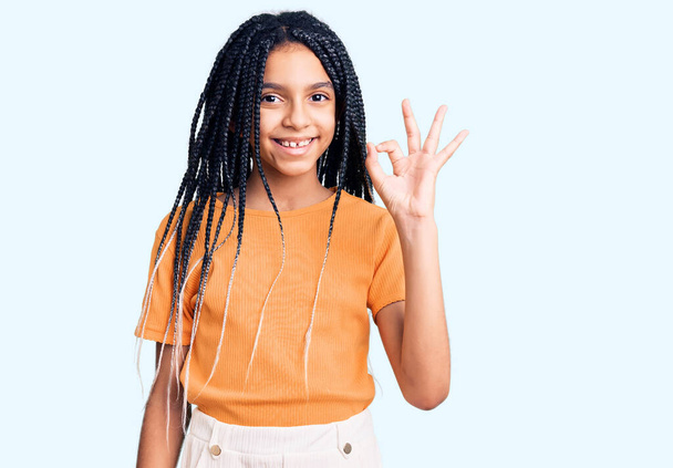 Roztomilé africké americká dívka na sobě ležérní oblečení s pozitivním úsměvem dělá v pořádku znamení s rukou a prsty. úspěšný výraz.  - Fotografie, Obrázek