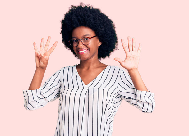 Nuori afrikkalainen amerikkalainen nainen yllään rento vaatteita ja laseja näyttää ja osoittaa sormilla numero yhdeksän hymyillen itsevarma ja onnellinen.  - Valokuva, kuva