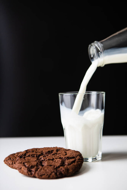ミルクをチョコレートクッキーでグラスに注ぐ。コピースペース - 写真・画像