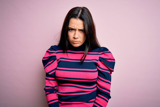Молода брюнетка елегантна жінка в смугастій сорочці над рожевим ізольованим фоном скептично і нервує, розчаровуючись через проблеми. Негативна людина
. - Фото, зображення