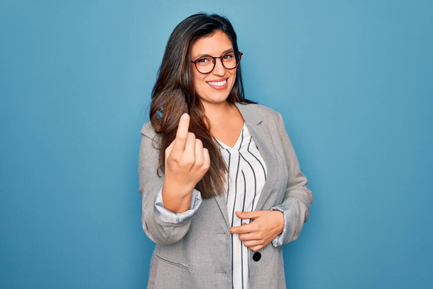 Jeune femme d'affaires hispanique portant des lunettes debout sur fond bleu isolé Beckoning venir ici geste avec la main invitant accueillant heureux et souriant - Photo, image