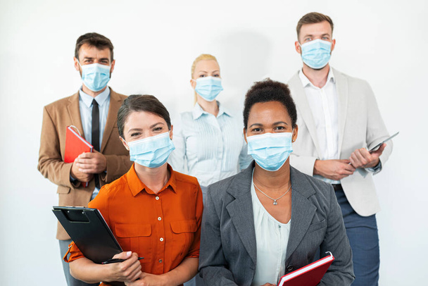 Group of students are looking at the camera, wearing masks because of the coronavirus - 写真・画像