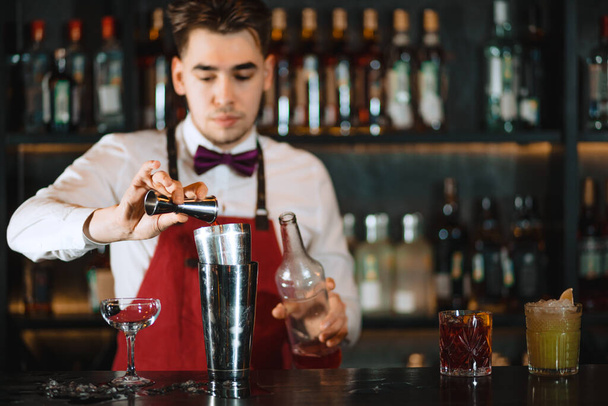 Barman pouring fresh cocktail from shaker into the glass on the bar counter - 写真・画像