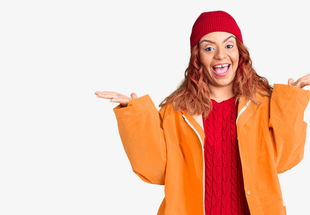 Jonge latijnse vrouw draagt winter casual kleding vieren overwinning met een vrolijke glimlach en winnaar uitdrukking met opgeheven handen  - Foto, afbeelding