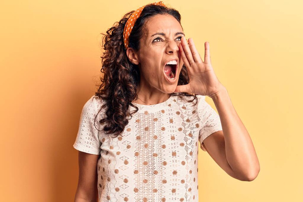 中世の美しい女性の叫びと大声で口の上に手で横に叫んでカジュアルなTシャツを着ている。コミュニケーションの概念.  - 写真・画像