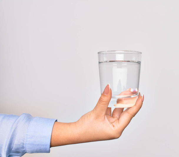 Mano de mujer joven caucásica sosteniendo un vaso de agua sobre un fondo blanco aislado
 - Foto, imagen