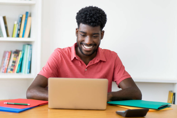 Afro american male student working at computer indoors at home - Foto, imagen