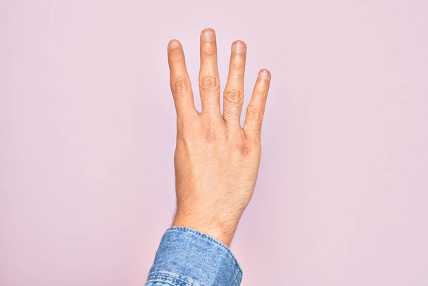 Mano de joven caucásico mostrando dedos sobre fondo rosa aislado contando número 4 mostrando cuatro dedos - Foto, imagen