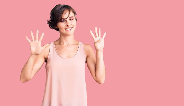 Beautiful young woman with short hair wearing casual style with sleeveless shirt showing and pointing up with fingers number nine while smiling confident and happy.  - Photo, Image