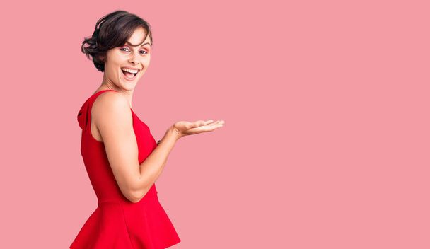 Beautiful young woman with short hair wearing casual style with sleeveless shirt pointing aside with hands open palms showing copy space, presenting advertisement smiling excited happy  - Foto, afbeelding