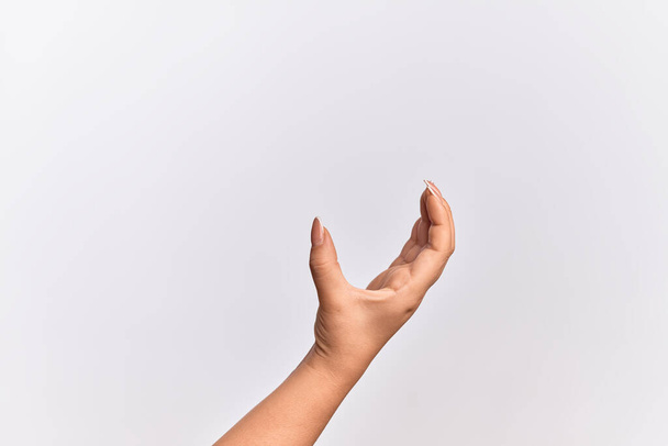 Ręka młodej białej kobiety zbierającej i zabierającej niewidzialną rzecz, trzymającej przedmiot palcami pokazującymi przestrzeń - Zdjęcie, obraz