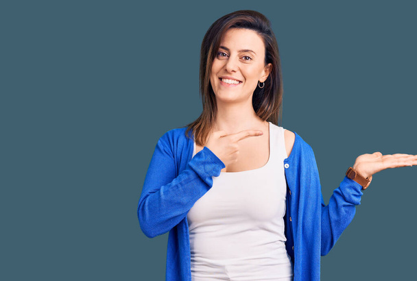 Young beautiful woman wearing casual clothes amazed and smiling to the camera while presenting with hand and pointing with finger.  - Photo, Image