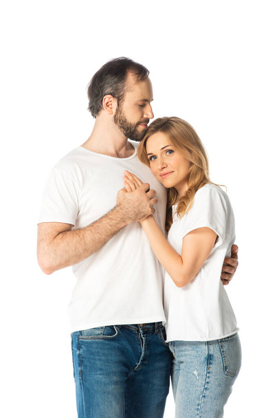 volwassen paar in witte t-shirts omarmen en houden handen geïsoleerd op wit - Foto, afbeelding