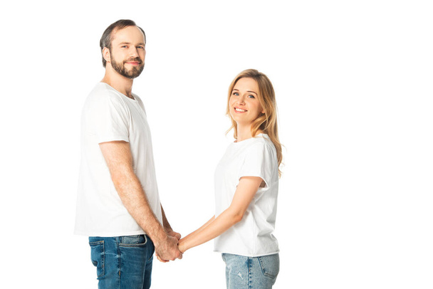 Seitenansicht eines erwachsenen Paares in weißen T-Shirts, das die Hände isoliert auf weiß hält - Foto, Bild