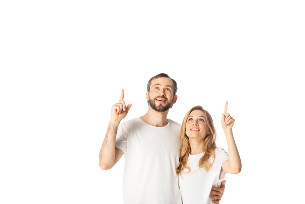 cheerful adult couple in white t-shirts pointing with fingers up isolated on white - 写真・画像