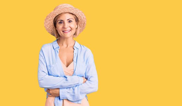 Jeune femme blonde portant un chapeau d'été visage heureux souriant avec les bras croisés regardant la caméra. personne positive.  - Photo, image