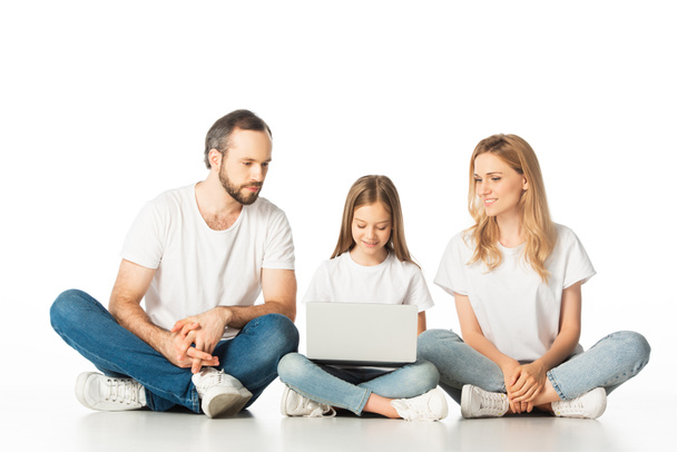 parents sitting on floor near happy daughter with laptop isolated on white - Valokuva, kuva