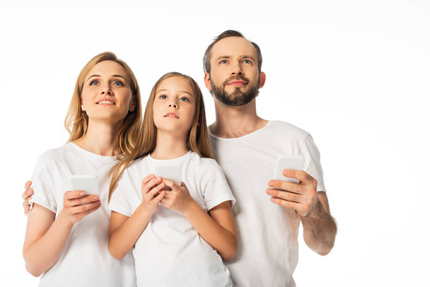 白に隔離されたスマートフォンを使って白いTシャツを着た家族 - 写真・画像