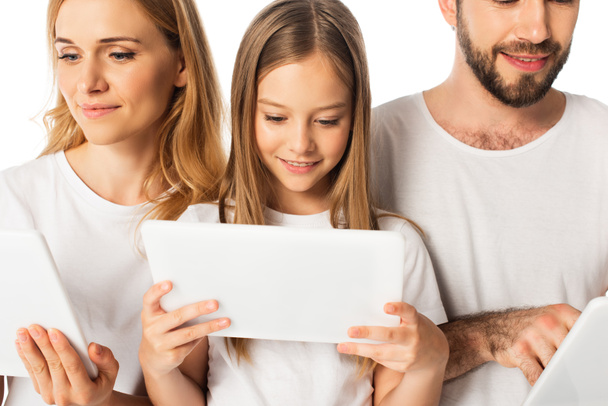 hymyilevä perhe valkoisissa t-paidoissa valkoisilla eristetyillä digitaalisilla tableteilla - Valokuva, kuva