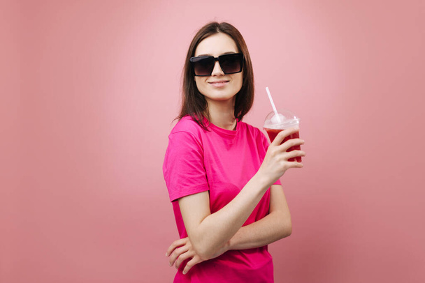 Stilvolles Mädchen in Sonnenbrille trinkt frischen Cocktail im Studio - Foto, Bild