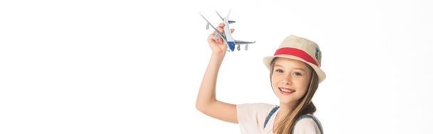 cheerful girl in hat with plane model isolated on white, panoramic shot - Photo, Image