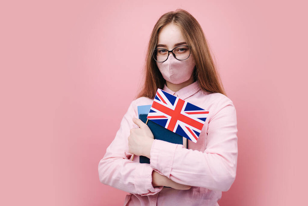 Сумна жінка в медичній масці тримає книги та британський прапор
 - Фото, зображення