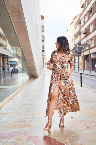 Beautiful young woman wearing fashionable clothes walking down the street - Фото, зображення
