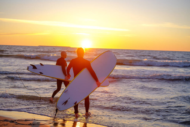 Surfistas irreconocibles entrando en el mar ondulado
 - Foto, Imagen