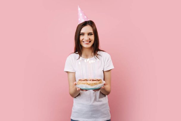 Usmívající se žena drží narozeninový dort a dívá se do kamery - Fotografie, Obrázek