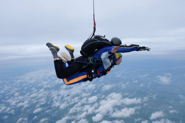 Çift kişilik paraşütle atlama. Bir kız ve eğitmeni bulutlu gökyüzünde uçuyorlar.. - Fotoğraf, Görsel