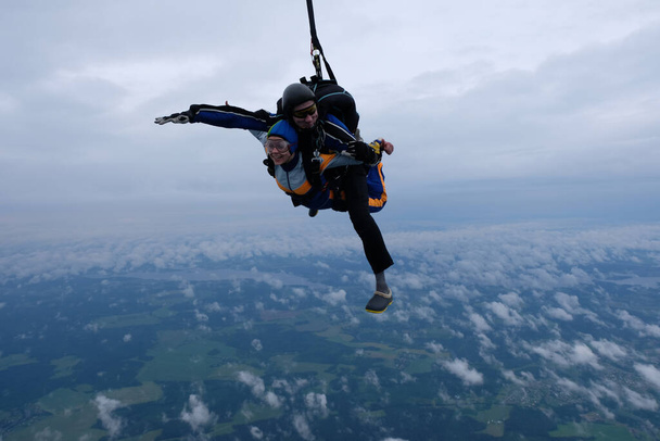 parachutisme en tandem. Une fille et son instructeur volent dans le ciel nuageux. - Photo, image